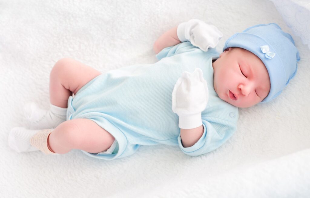 Bebê dormindo com roupinha azul e gorro