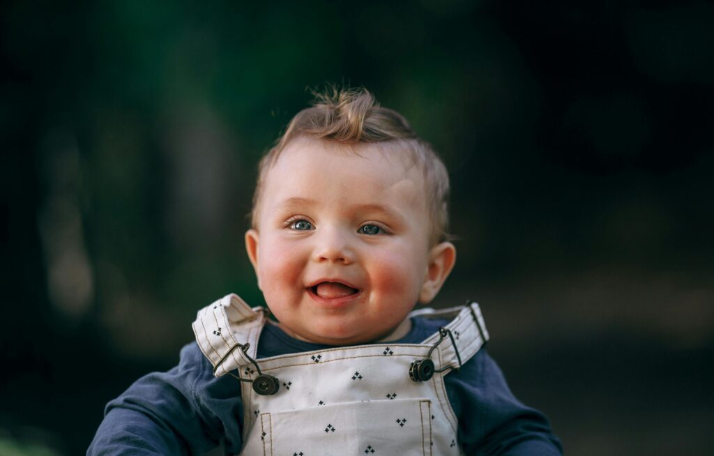 Bebê sorridente com macacão claro ao ar livre