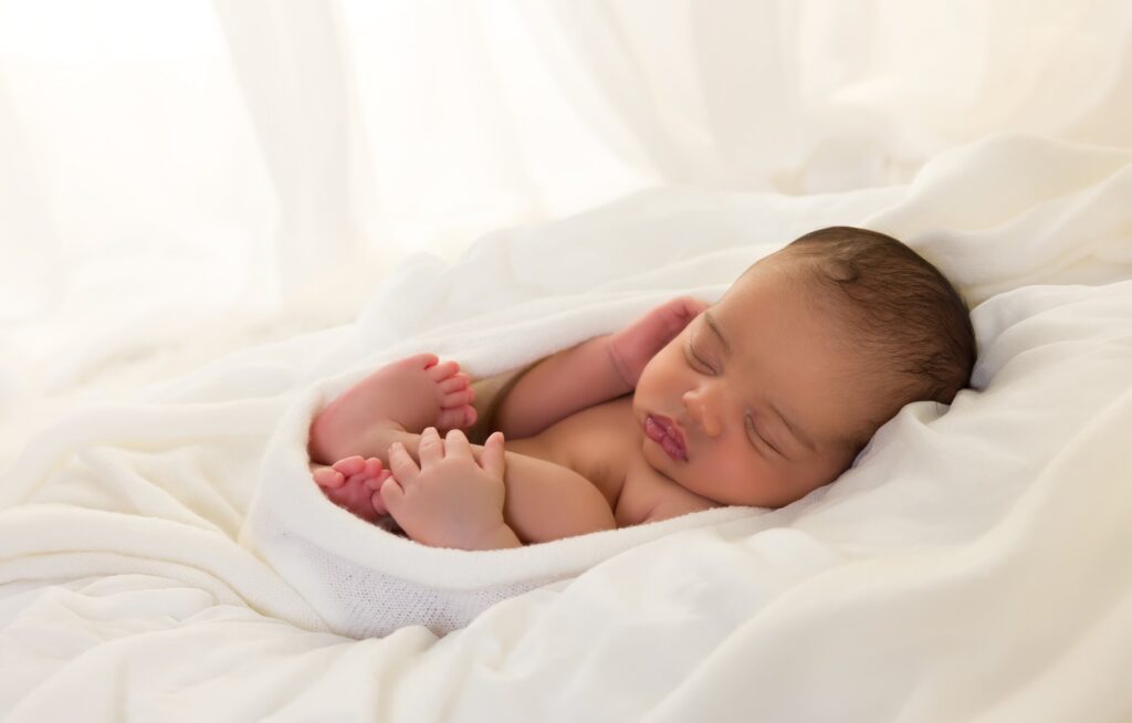 Bebê dormindo envolto em tecido branco