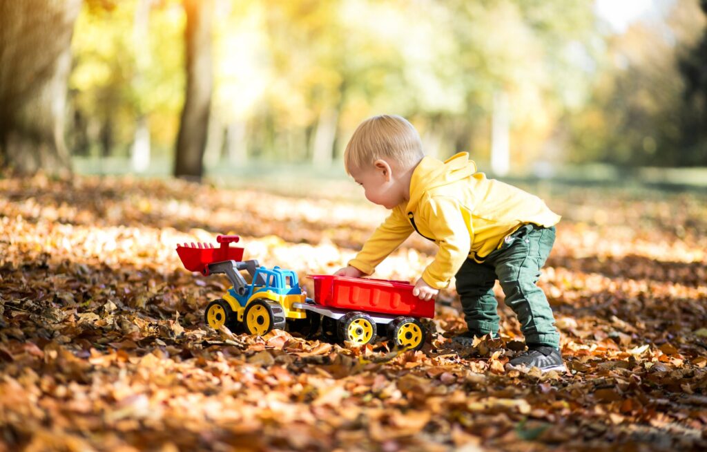 Criança brincando com caminhão de brinquedo no outono