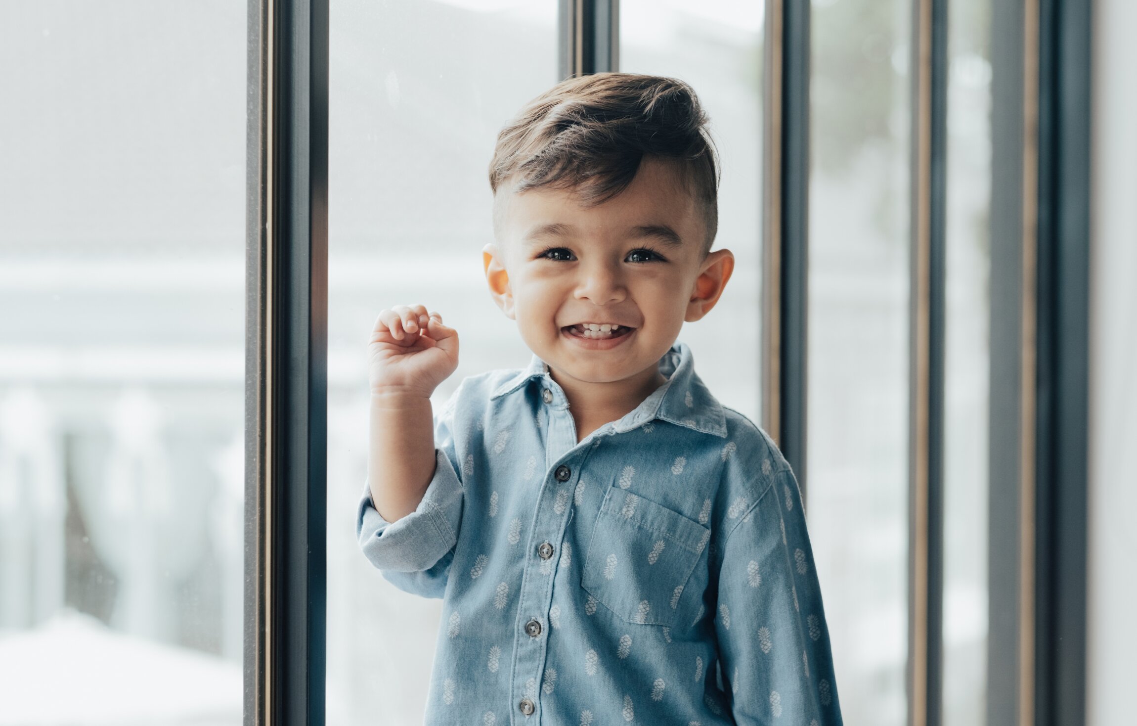 Criança sorrindo ao lado de uma janela