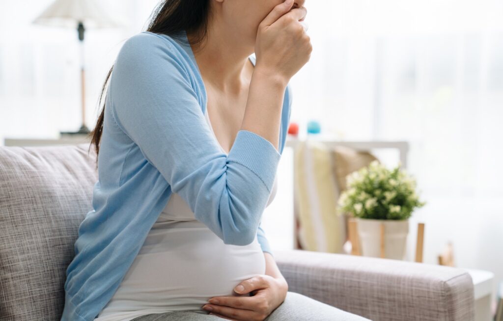 Mulher grávida com expressão de dor na barriga