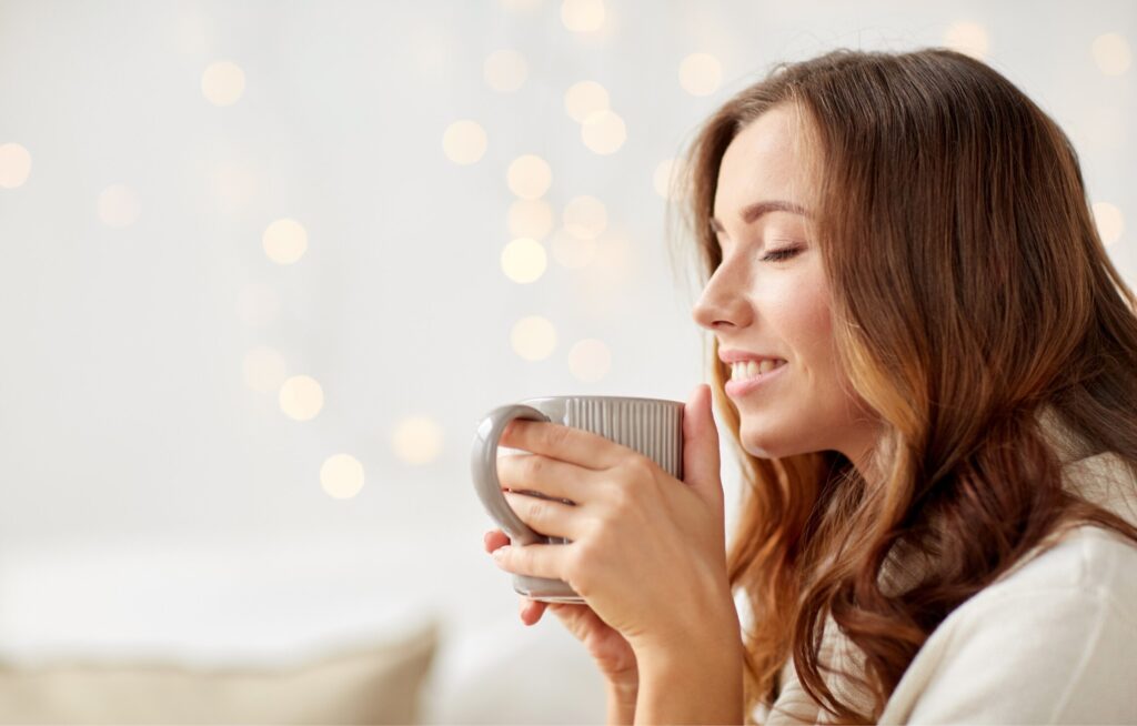 Mulher sorrindo ao segurar uma caneca quente