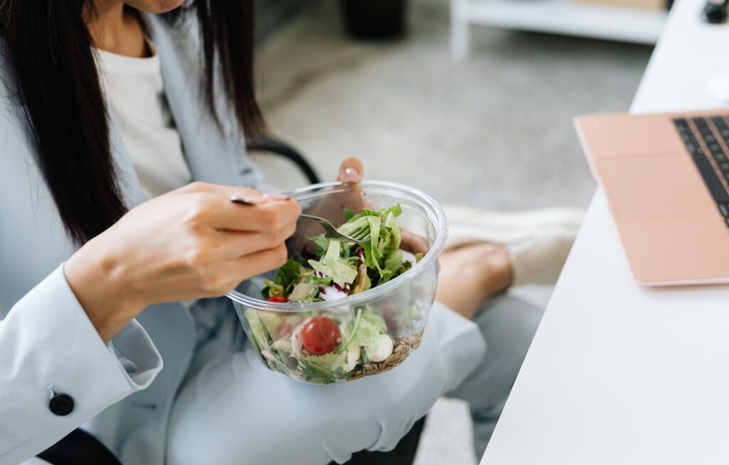 Pessoa comendo salada enquanto trabalha no escritório.