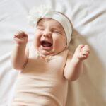 Bebê sorrindo com flores no cabelo em fundo claro