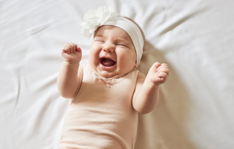 Bebê sorrindo com flores no cabelo em fundo claro