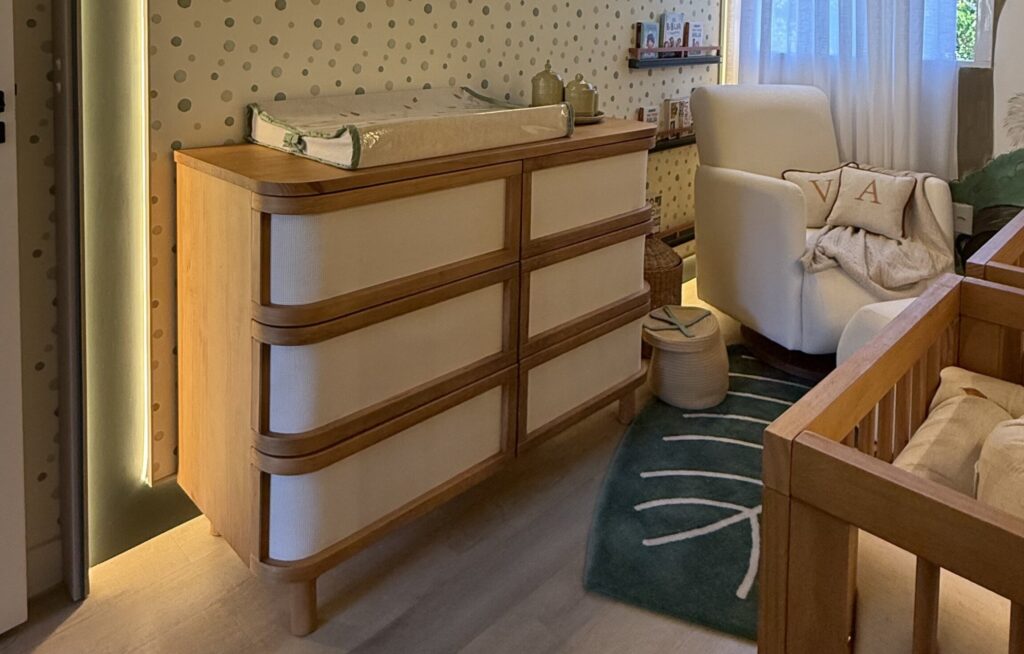 Cômoda de madeira em quarto de bebê com decoração suave