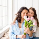 Mãe e filha abraçadas com flores de tulipas.