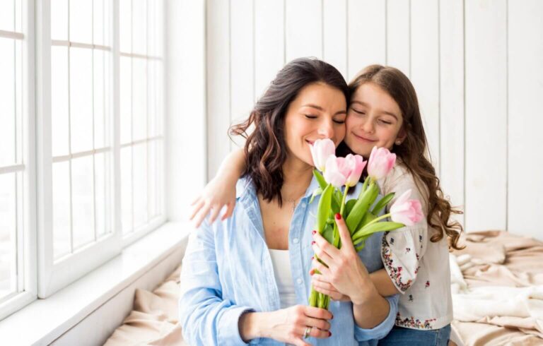 Mãe e filha abraçadas com flores de tulipas.