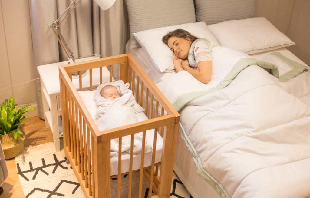 Mãe dormindo ao lado do berço do bebê