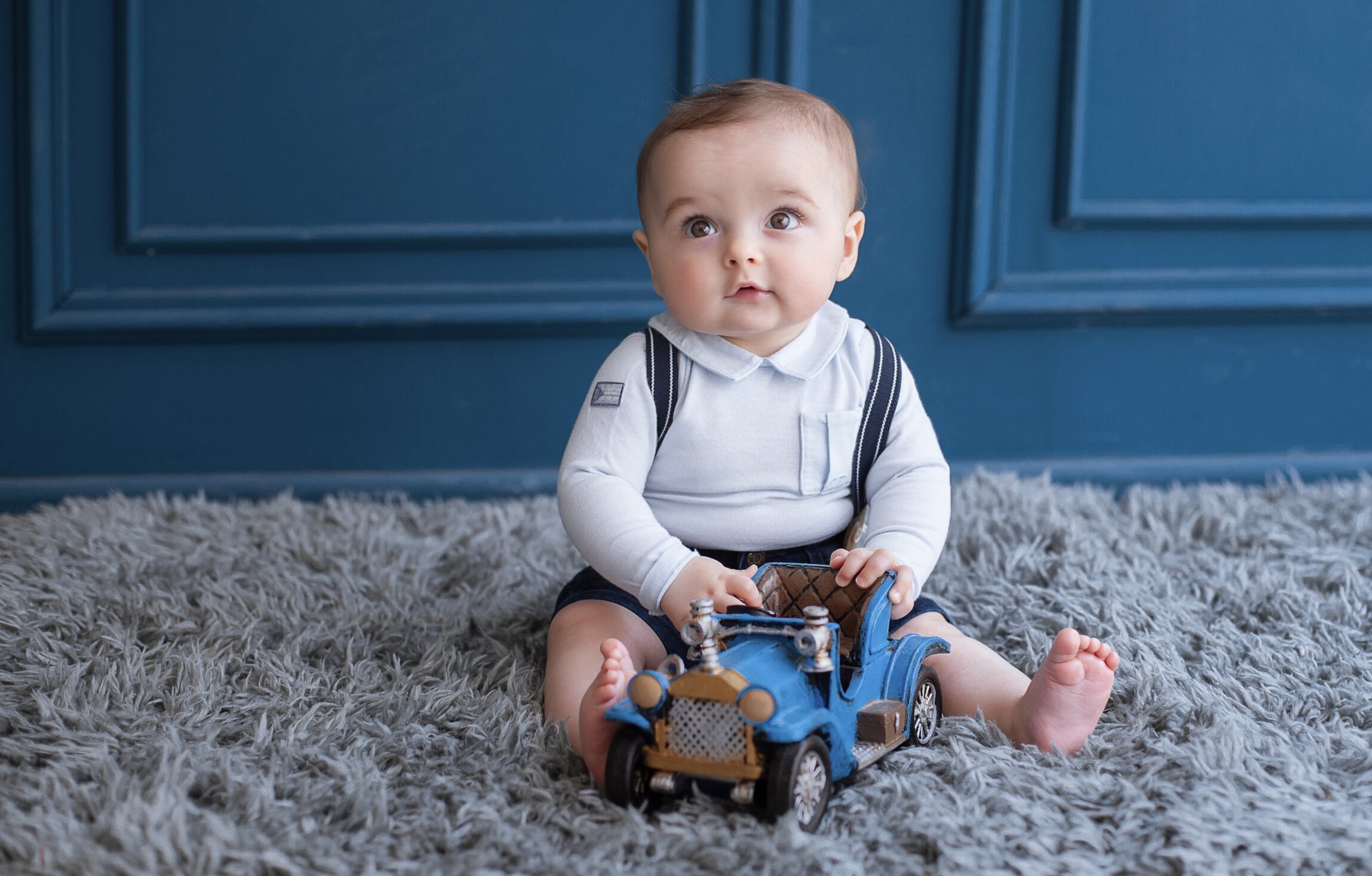 Bebê sentado com carro de brinquedo azul
