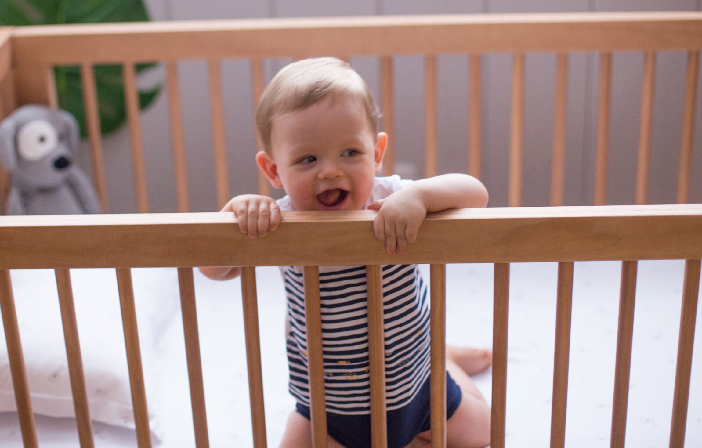 Bebê sorridente em berço de madeira