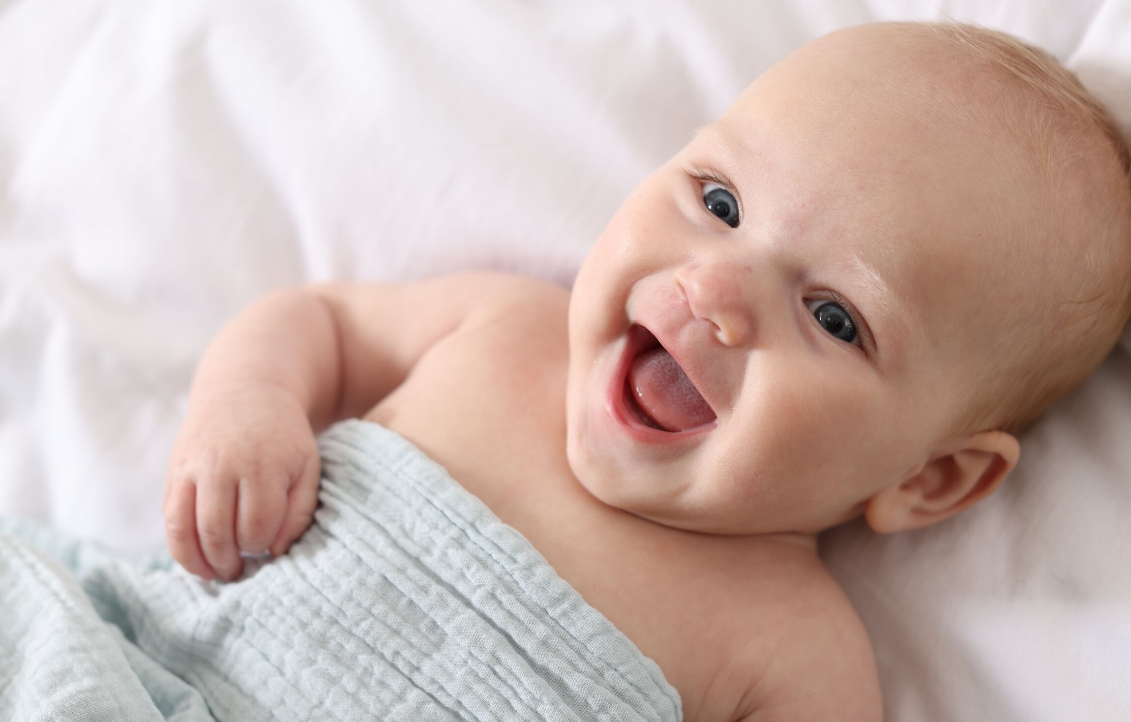 Bebê sorridente enrolado em um pano azul