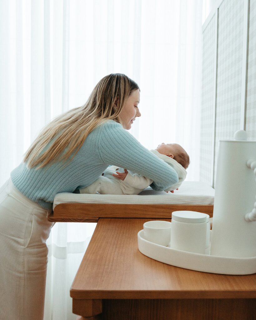 Mãe acariciando bebê na troca de fraldas
