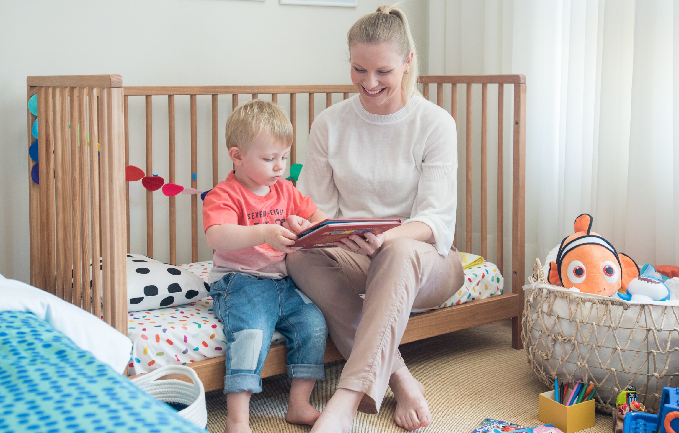 Mãe e filho lendo em um quarto infantil